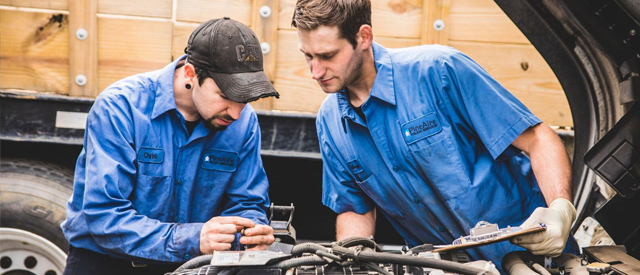Truck repair maintenance with two Pine Aire Truck employees with hands in engine