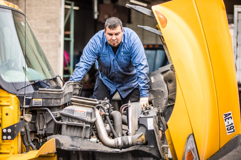 A picture of a diesel truck technician looking into the engine of a semi truck