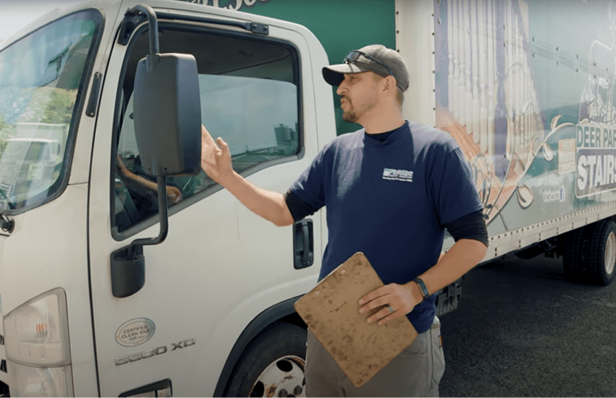 A picture of a diesel technician peering into the window of a box truck