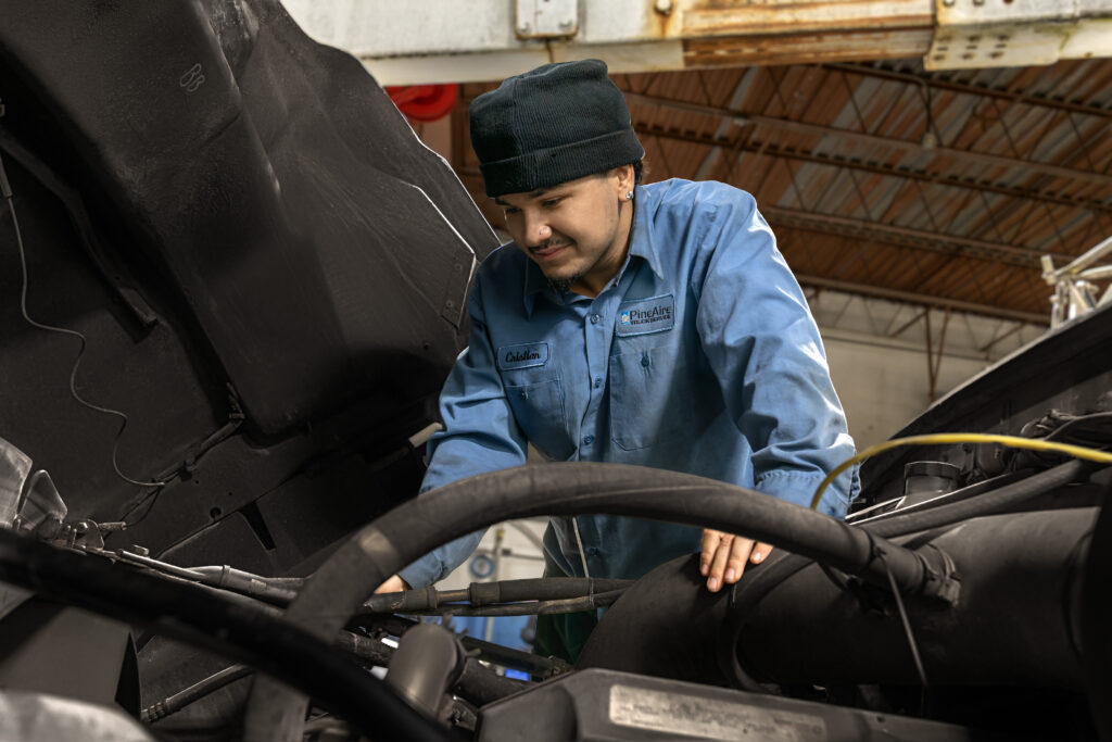 A picture of a truck repair technician in a semi truck hood